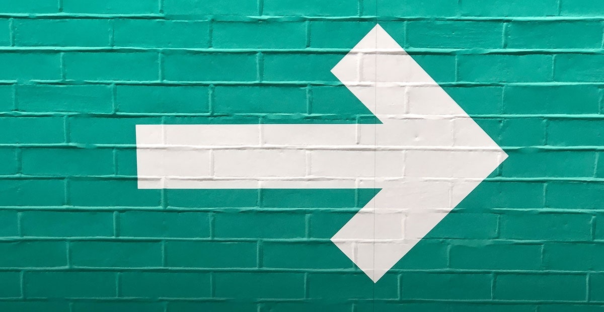 Turquoise Brick Wall With White Arrow Pointing Right