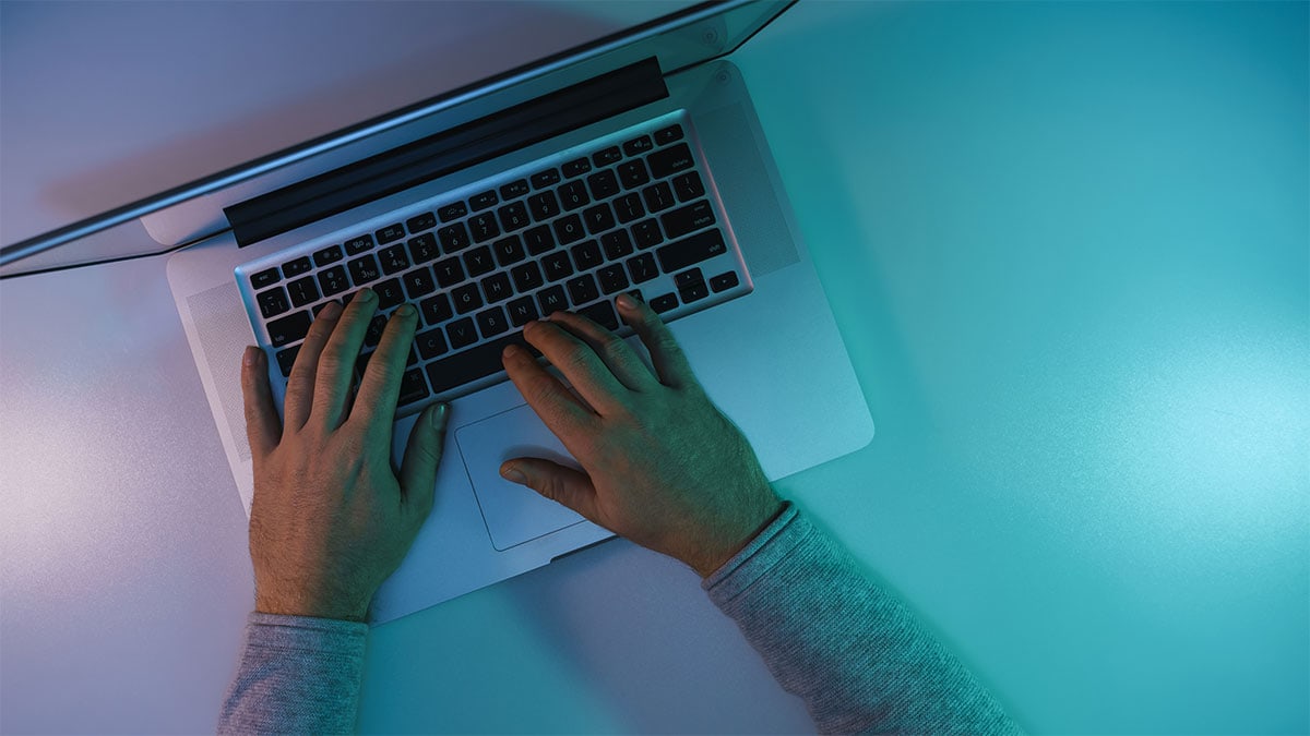 Top Down View of a Man Working on a Silver MacBook Pro at Night